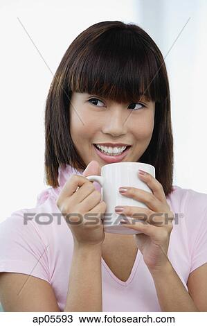 Young woman holding mug, smiling View Large Photo Image Stock Image - Young woman holding mug, smiling. Fotosearch