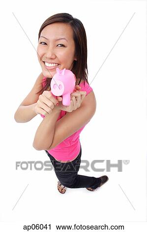 Young woman holding piggy bank, smiling up at camera View Large Photo Image Stock Image - Young woman holding piggy bank, smiling up at camera. Fotosearch