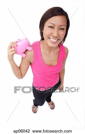 Young woman holding piggy bank, smiling View Large Photo Image Stock Image - Young woman holding piggy bank, smiling. Fotosearch
