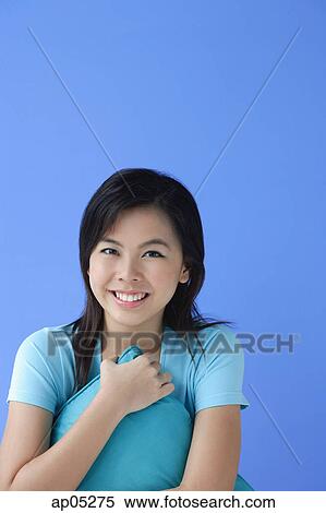 Stock Photography - Young woman hugging pillow, looking at camera. Fotosearch