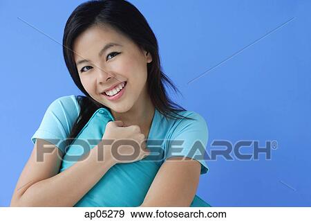 Stock Photo - Young woman hugging pillow, portrait. Fotosearch