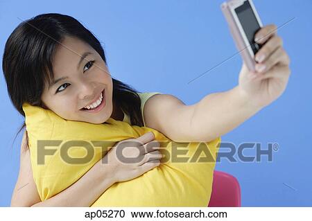 Young woman hugging pillow, using mobile phone to take a picture View Large Photo Image Stock Image - Young woman hugging pillow, using mobile phone to take a picture. Fotosearch