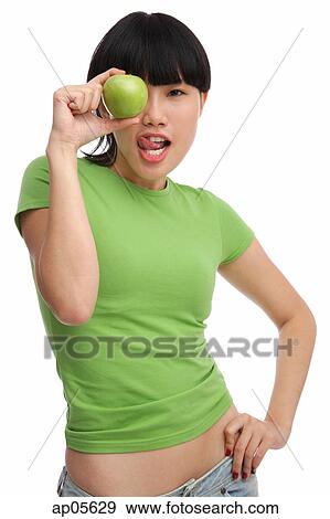 Young woman in green T-shirt, holding green apple View Large Photo Image Stock Photo - Young woman in green T-shirt, holding green apple. Fotosearch