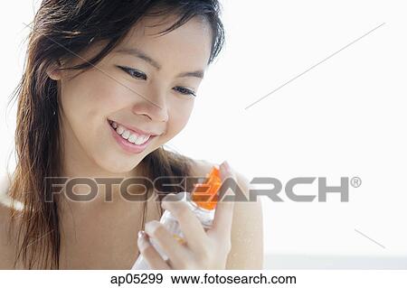 Young woman looking at bottle, smiling View Large Photo Image Stock Photo - Young woman looking at bottle, smiling. Fotosearch