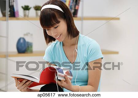Young woman looking through magazine View Large Photo Image Stock Photo - Young woman looking through magazine. Fotosearch