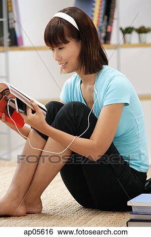 Young woman looking through magazine, wearing earphones View Large Photo Image Stock Photograph - Young woman looking through magazine, wearing earphones. Fotosearch