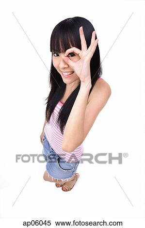 Stock Photography - Young woman making OK sign, looking through fingers. Fotosearch