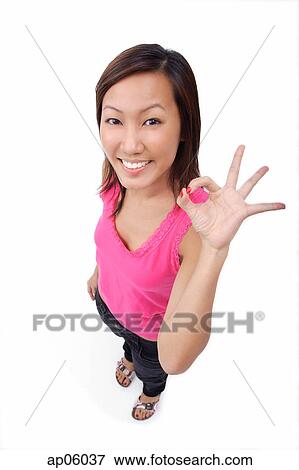 Stock Photo - Young woman making OK sign, smiling up at camera. Fotosearch