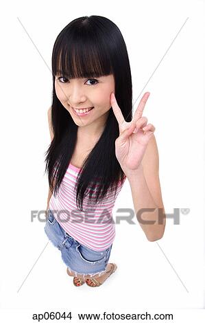 Picture - Young woman making peace sign, smiling up at camera. Fotosearch