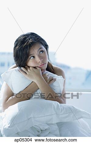 Young woman on bed, embracing pillow, looking away View Large Photo Image Picture - Young woman on bed, embracing pillow, looking away. Fotosearch