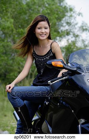 Young woman on motorcycle, smiling at camera View Large Photo Image Stock Image - Young woman on motorcycle, smiling at camera. Fotosearch