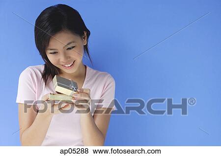 Stock Photo - Young woman opening small gift box. Fotosearch