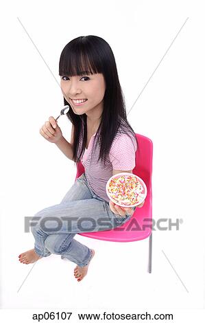 Stock Photo - Young woman sitting, holding bowl of ice cream. Fotosearch