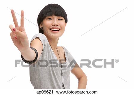 Young woman smiling at camera, making peace sign View Large Photo Image Stock Image - Young woman smiling at camera, making peace sign. Fotosearch