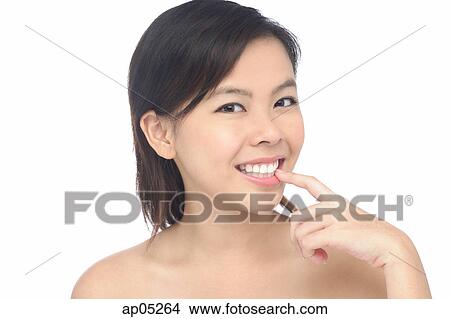 Young woman smiling, looking at camera, finger on mouth View Large Photo Image Picture - Young woman smiling, looking at camera, finger on mouth. Fotosearch