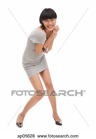 Stock Photo - Young woman standing against white background, smiling at camera. Fotosearch