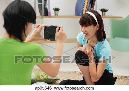 Young woman taking a picture of another young woman View Large Photo Image Stock Photograph - Young woman taking a picture of another young woman. Fotosearch