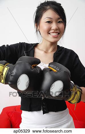 Young woman wearing boxing gloves, smiling at camera View Large Photo Image Stock Photo - Young woman wearing boxing gloves, smiling at camera. Fotosearch