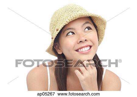 Stock Photo - Young woman wearing hat, looking away, hand on chin. Fotosearch