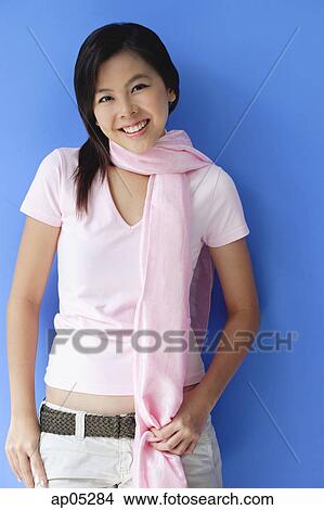 Young woman wearing scarf around her neck, smiling at camera View Large Photo Image Picture - Young woman wearing scarf around her neck, smiling at camera. Fotosearch