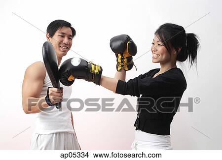 Picture - Young woman with boxing gloves, practicing with trainer. Fotosearch