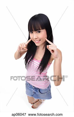 Young woman with fingers on cheek, smiling at camera View Large Photo Image Stock Photo - Young woman with fingers on cheek, smiling at camera. Fotosearch