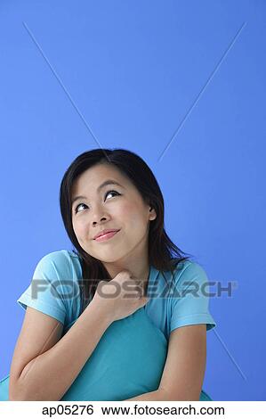 Stock Photograph - Young woman with pillow, looking up. Fotosearch