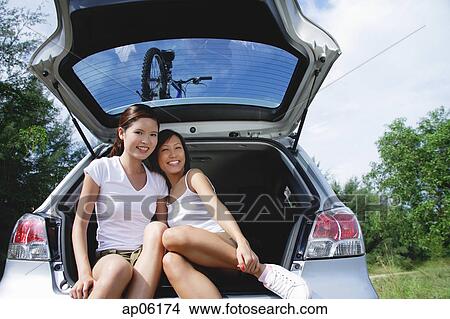 Young women sitting in boot of car, portrait View Large Photo Image Picture - Young women sitting in boot of car, portrait. Fotosearch