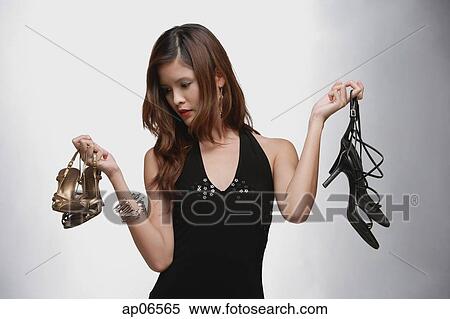 Stock Image - Woman in black top, holding two pairs of shoes. Fotosearch - Search Stock Photos, Mural Pictures, Photographs, and Photo Clipart