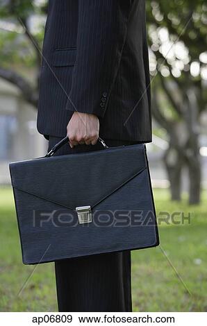 Businessman holding briefcase, side view View Large Photo Image Stock Photo - Businessman holding briefcase, side view. Fotosearch