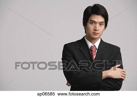 Businessman looking at camera, arms crossed View Large Photo Image Stock Photography - Businessman looking at camera, arms crossed. Fotosearch