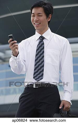 Businessman looking at mobile phone View Large Photo Image Picture - Businessman looking at mobile phone. Fotosearch