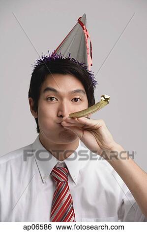 Stock Photograph - Businessman wearing party hat and using noisemaker. Fotosearch