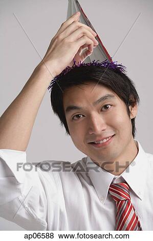 Businessman wearing party hat, looking at camera View Large Photo Image Stock Photo - Businessman wearing party hat, looking at camera. Fotosearch