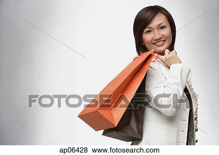 Businesswoman carrying shopping bags over shoulder, smiling View Large Photo Image Stock Photo - Businesswoman carrying shopping bags over shoulder, smiling. Fotosearch