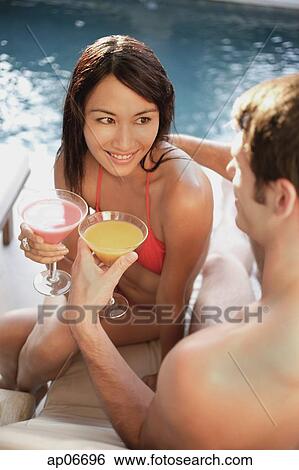 Couple by swimming pool, toasting with drinks View Large Photo Image Stock Photograph - Couple by swimming pool, toasting with drinks. Fotosearch