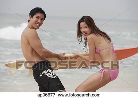 Couple fighting for surfboard View Large Photo Image Stock Photo - Couple fighting for surfboard. Fotosearch
