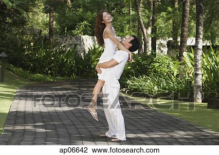 Couple in garden, man carrying woman View Large Photo Image Stock Image - Couple in garden, man carrying woman. Fotosearch