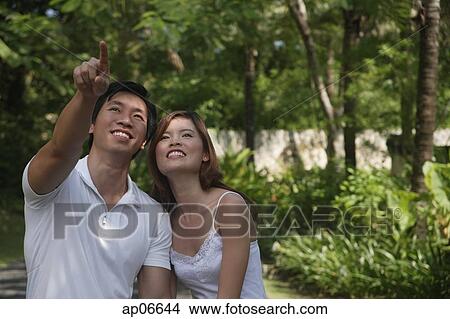 Couple in garden, man pointing upwards View Large Photo Image Picture - Couple in garden, man pointing upwards. Fotosearch