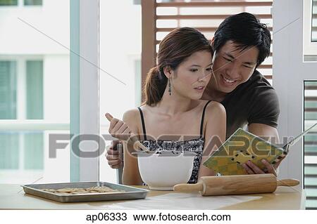Couple in kitchen, looking at cookbook View Large Photo Image Stock Image - Couple in kitchen, looking at cookbook. Fotosearch