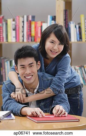 Couple in library, woman embracing man from behind View Large Photo Image Stock Image - Couple in library, woman embracing man from behind. Fotosearch