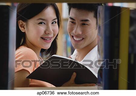 Couple in library, woman looking at camera View Large Photo Image Stock Photograph - Couple in library, woman looking at camera. Fotosearch