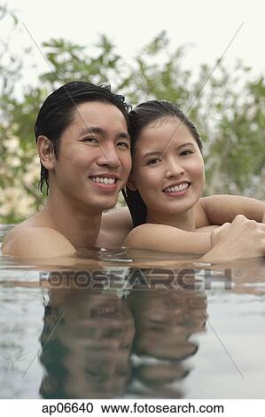 Couple in swimming pool, head above water, smiling at camera View Large Photo Image Stock Image - Couple in swimming pool, head above water, smiling at camera. Fotosearch