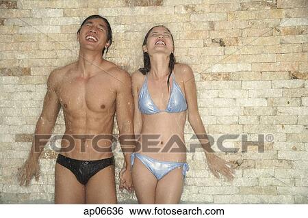Couple in swimwear, eyes closed, water falling on them View Large Photo Image Stock Photograph - Couple in swimwear, eyes closed, water falling on them. Fotosearch