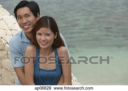 Couple looking at camera, sea behind them View Large Photo Image Stock Photo - Couple looking at camera, sea behind them. Fotosearch