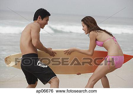 Couple on beach, fighting for surfboard View Large Photo Image Stock Photograph - Couple on beach, fighting for surfboard. Fotosearch