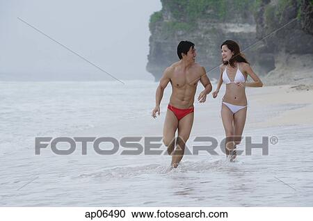 Couple running along beach View Large Photo Image Stock Image - Couple running along beach. Fotosearch