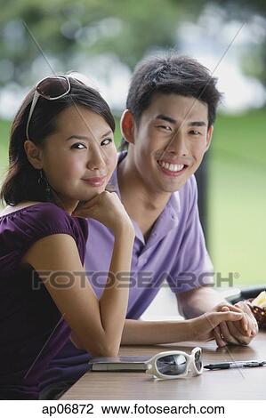 Couple sitting at cafe, smiling at camera View Large Photo Image Stock Image - Couple sitting at cafe, smiling at camera. Fotosearch