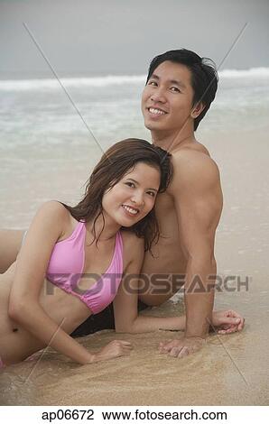 Couple sitting on beach, looking at camera, portrait View Large Photo Image Stock Image - Couple sitting on beach, looking at camera, portrait. Fotosearch
