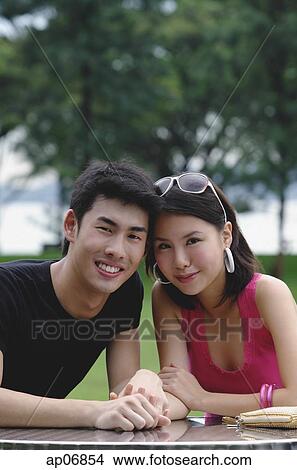 Couple sitting side by side, smiling at camera View Large Photo Image Picture - Couple sitting side by side, smiling at camera. Fotosearch